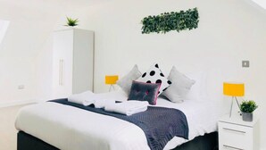 A modern bedroom with a bed, white wardrobe, and two bedside lamps.