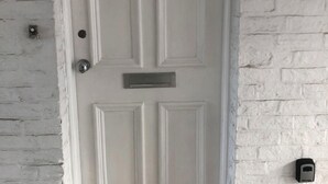 Une porte blanche avec une fente pour le courrier et un carillon.