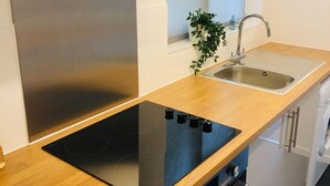 Une cuisine moderne équipée d’un réfrigérateur en acier inoxydable, d’un évier et d’une plaque de cuisson à induction.