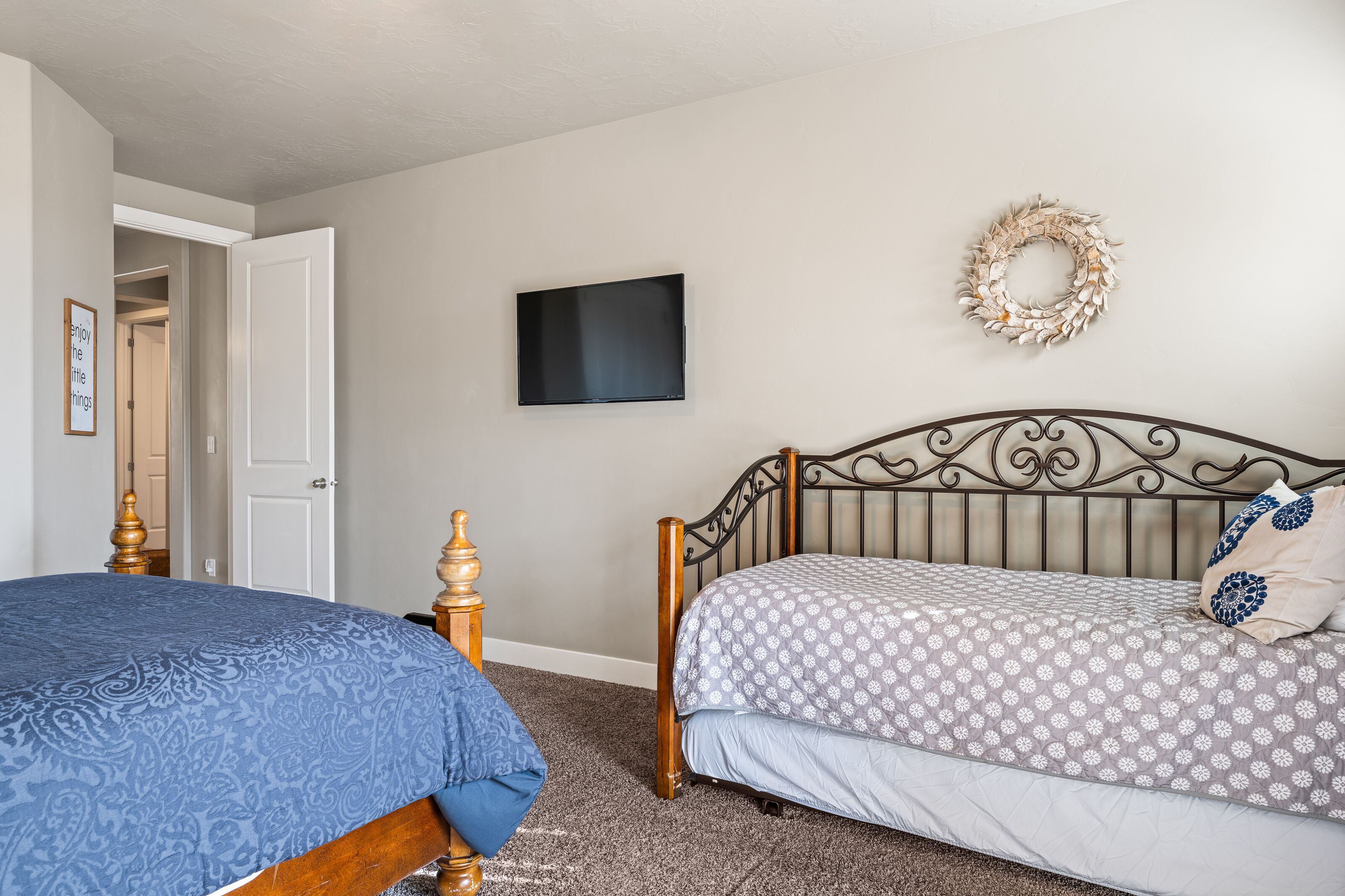Une chambre avec deux lits, un téléviseur à écran plat, une guirlande décorative et une porte donnant sur une autre pièce.