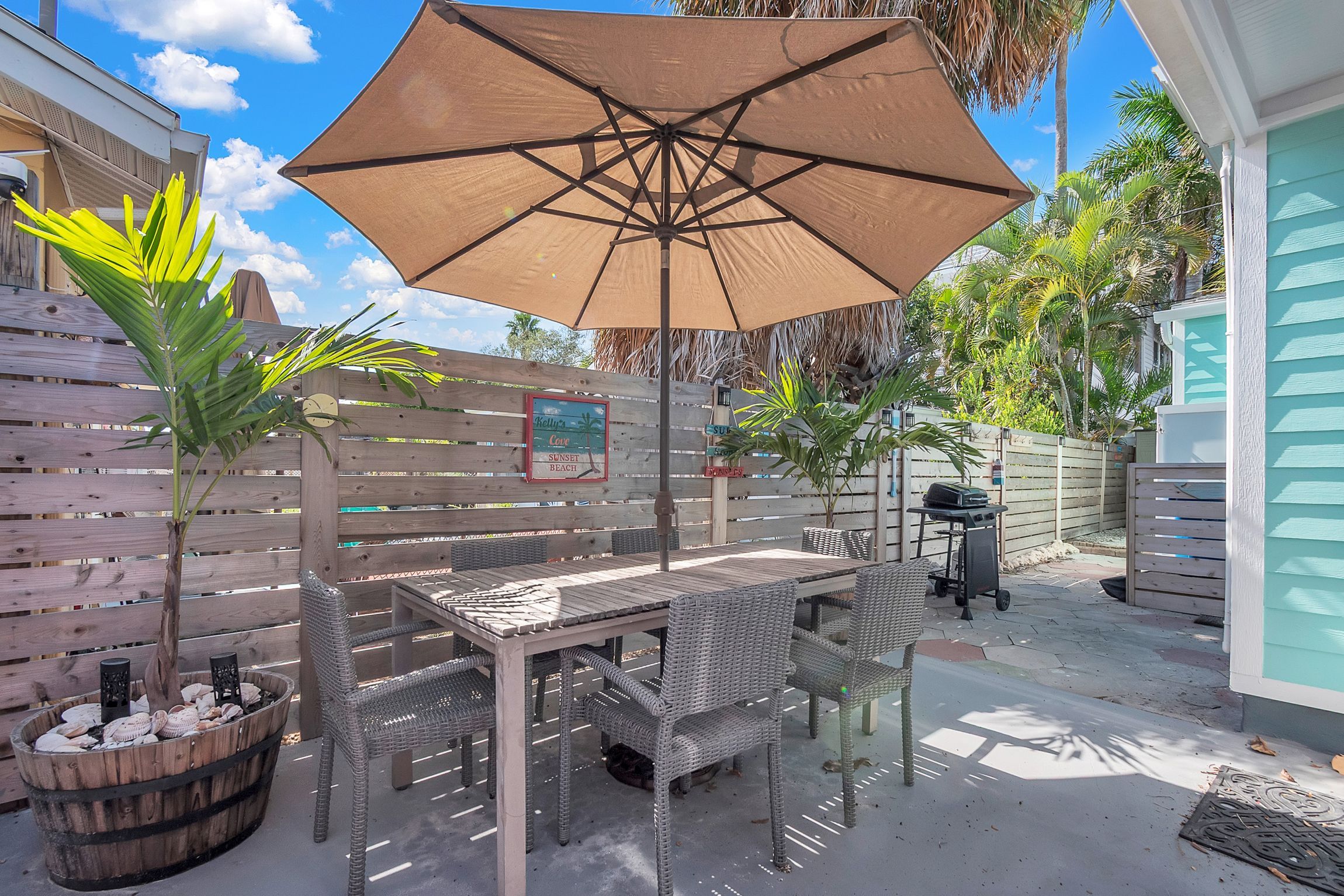 Un patio con mesa y sillas, un paraguas grande y una valla de madera.
