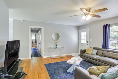 A modern living room with a flat-screen TV, leather sofa, and a ceiling fan.