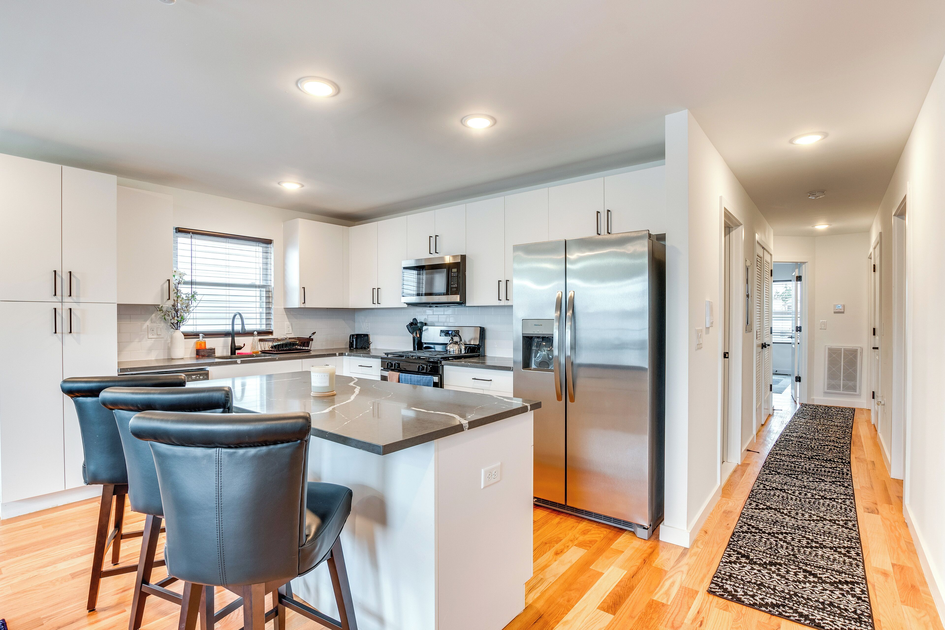 A modern kitchen with white cabinets, stainless steel appliances, and a central island with bar stools.