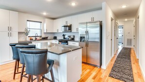 A modern kitchen with white cabinets, stainless steel appliances, and a central island with bar stools. - Modern Elizabeth Apartment ~ 1 Mi to Train Station (Elizabeth)