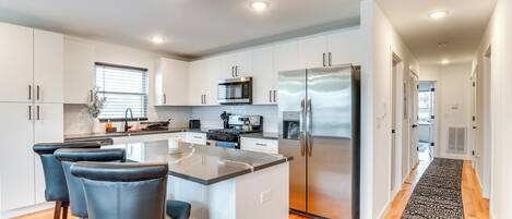A modern kitchen with white cabinets, stainless steel appliances, and a central island with bar stools.
