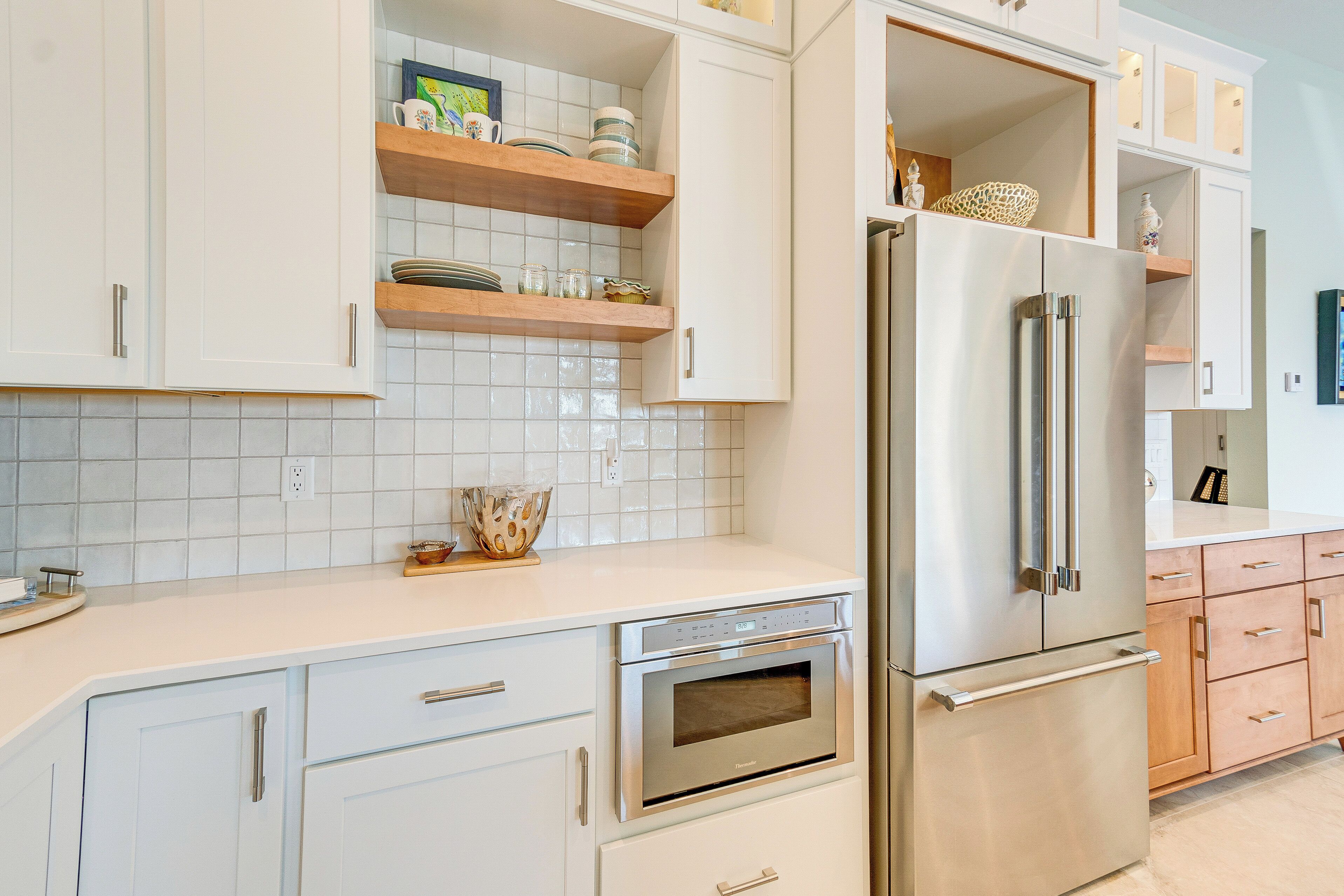 A modern kitchen with white cabinets, a stainless steel refrigerator, and an oven.