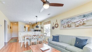 A living room with a gray sofa, a wooden coffee table, and a dining area with white chairs and a table.