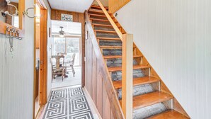 Eine Holztreppe mit einem gemusterten Teppich führt zu einem Zimmer mit Deckenventilator und einem Schild mit der Aufschrift 'Welcome'.
