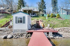 A small cabin with a dock leading to a rocky shore, surrounded by houses and trees. - Waterfront Wolcott Vacation Rental w/ Deck & Views (Wolcott)