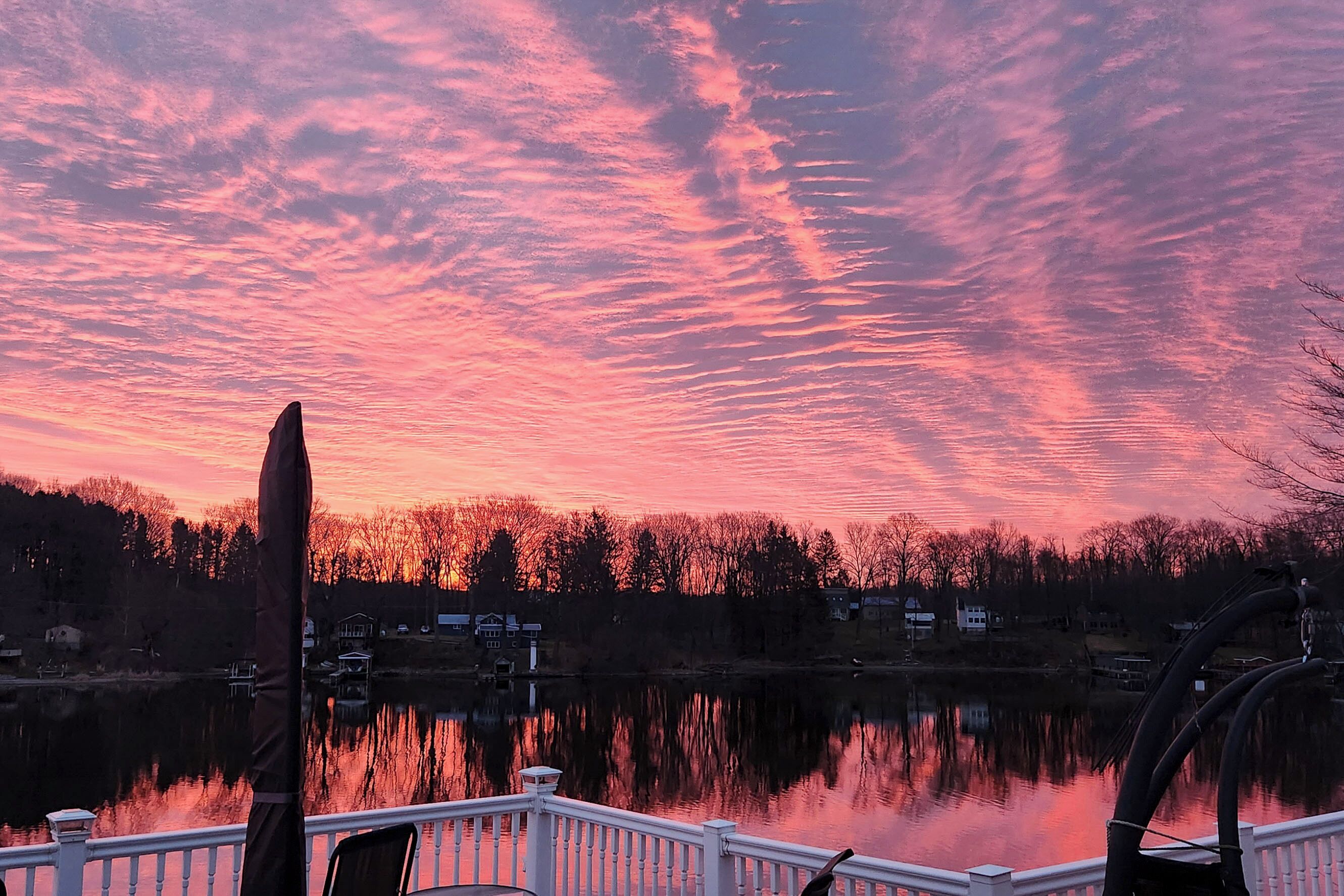 A lakeside view with a dock and a reflection of the sky.