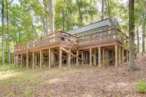 Une cabane en bois dotée d’une terrasse, entourée d’arbres.