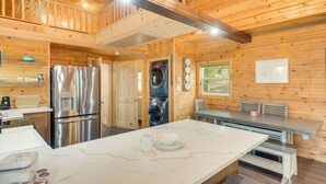 A modern kitchen with stainless steel appliances, a marble countertop, and wooden walls.