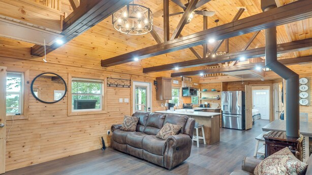 A spacious living area with a leather sofa, wooden walls, and a kitchen in the background.