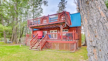A cabin with a wooden deck, a staircase, and a blue exterior wall.