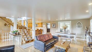A spacious living area with a sofa, coffee table, and dining table. A staircase leads to an upper level with a kitchen and dining area.