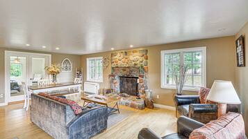 A spacious living room with a stone fireplace, a dining area, and a seating area with sofas and a coffee table.