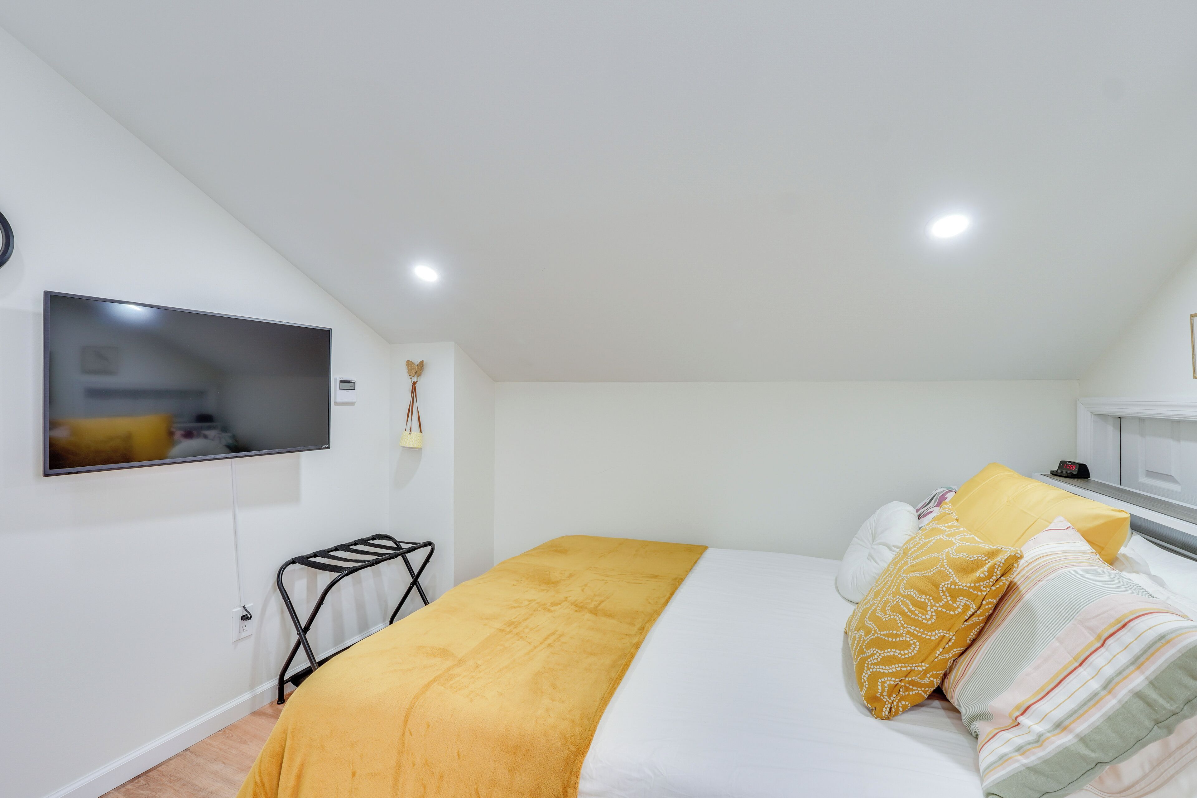 Un dormitorio con una cama, un televisor instalado en la pared y un radiador.