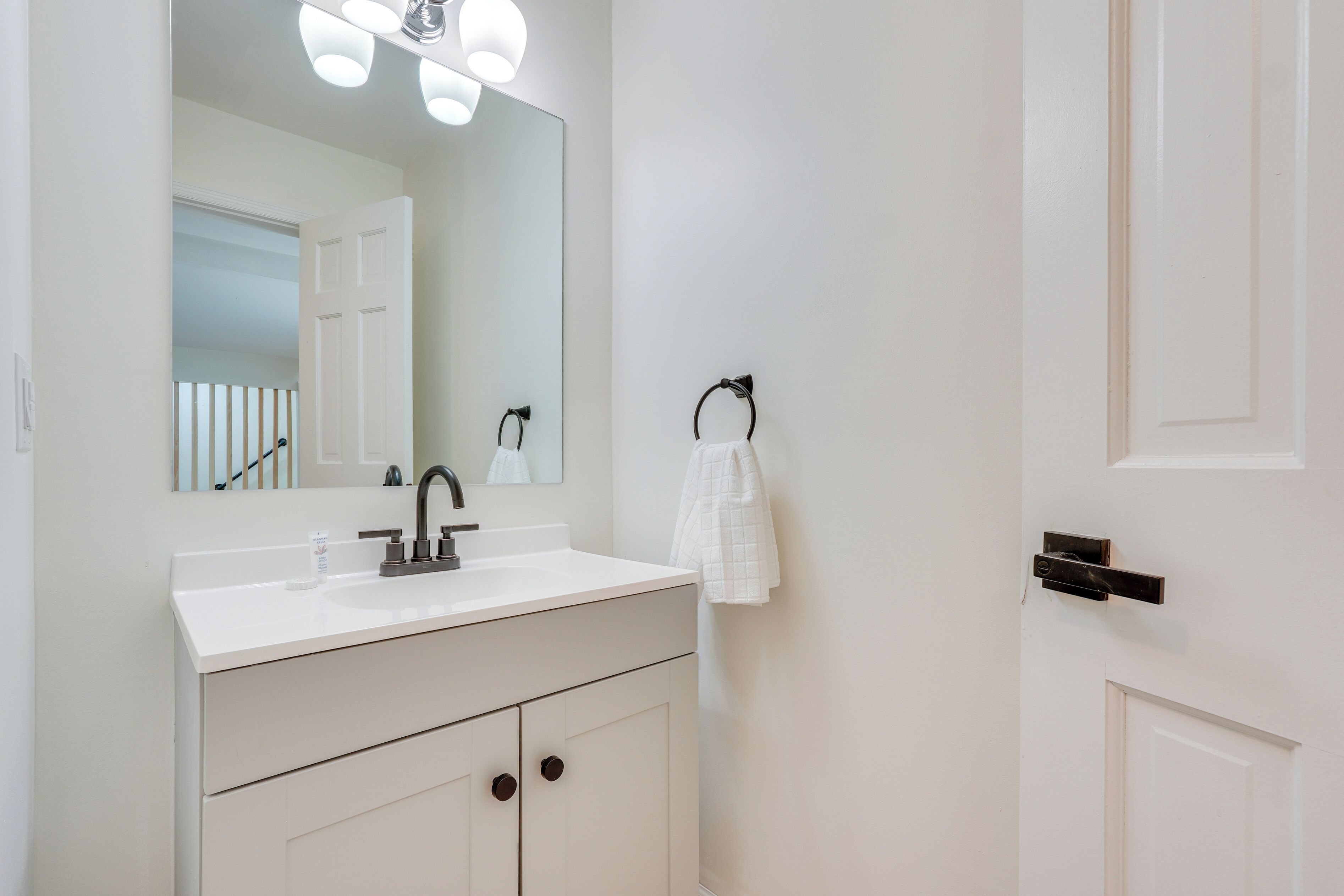 A bathroom with a white sink, mirror, and towel rack.