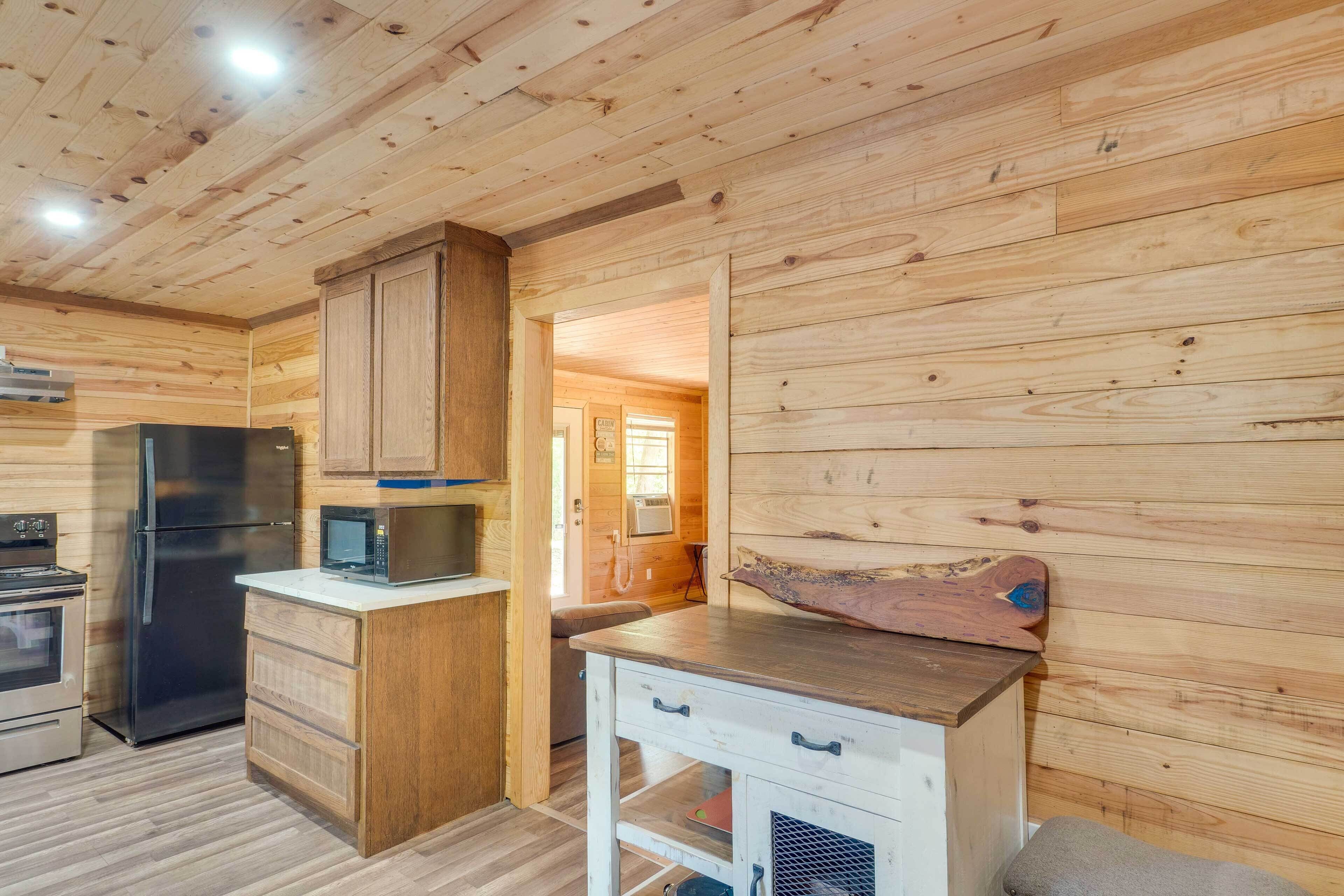 A wooden interior with a kitchen area including a refrigerator, microwave, and wooden cabinets.