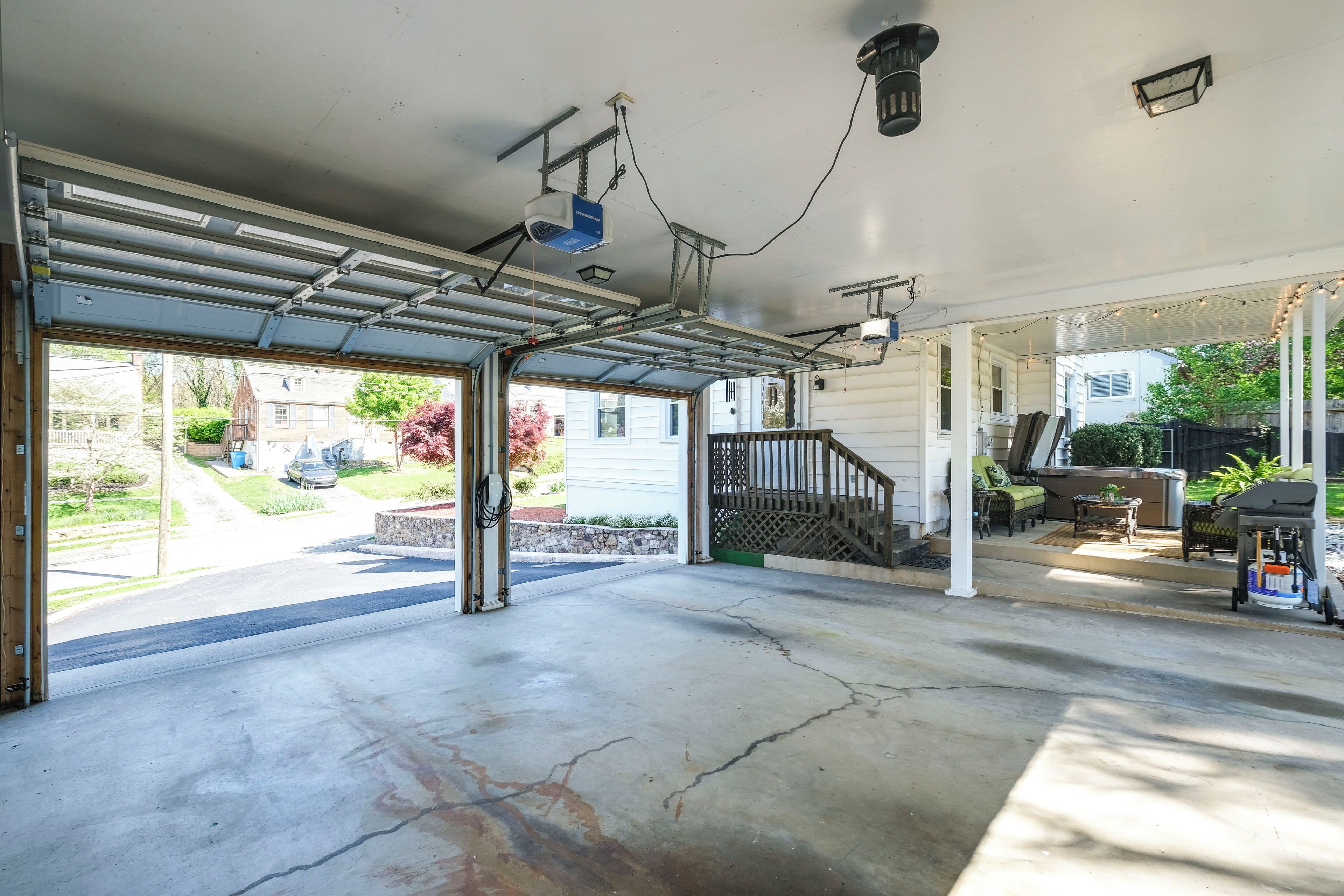 A garage with a concrete floor, a covered area with a staircase, and a patio with outdoor furniture.