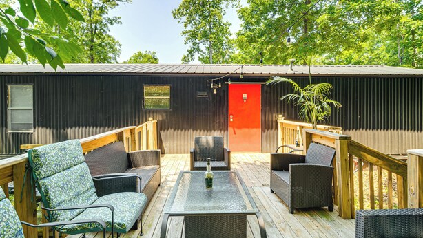 Eine Terrasse mit Korbmöbeln, einer roten Tür und einem Metallgeländer.