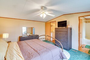 Une chambre à coucher comprenant un lit, une commode, un téléviseur et un ventilateur de plafond.