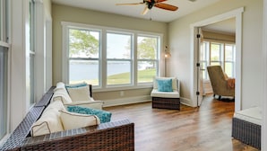 A spacious living room with a large window overlooking a body of water, a ceiling fan, and a wicker sofa with cushions. - 'sunset Paradise' on Weiss Lake w/ Private Dock! (Centre)