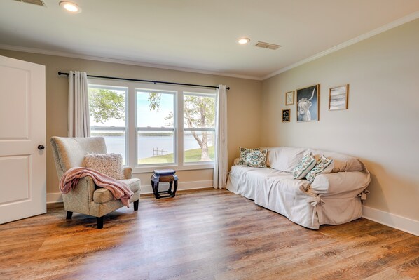 A room with a large window, a chair, a sofa, and a small table.