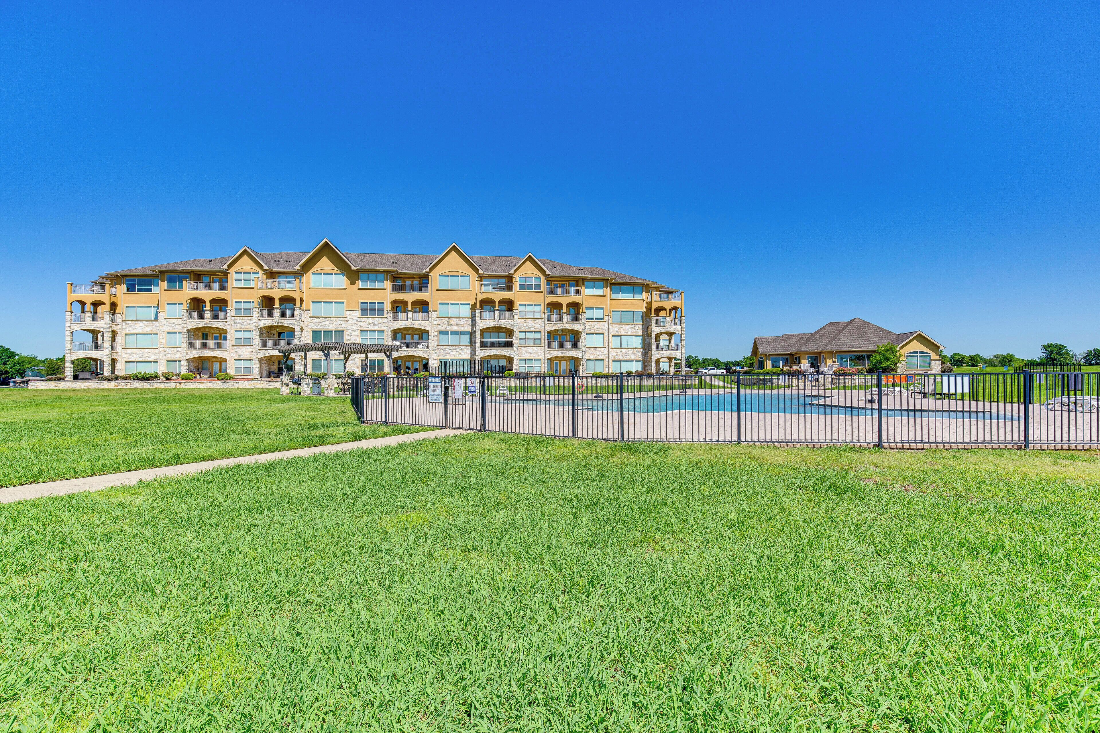 A multi-story hotel with a swimming pool and a fenced outdoor area.
