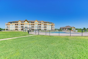 A multi-story hotel with a swimming pool and a fenced outdoor area.
