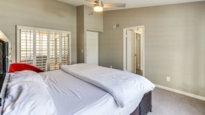 Una camera da letto con un letto, una ventola a soffitto e una porta.
