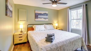 A neatly made bed with a quilt, two bedside lamps, a ceiling fan, and a window with curtains. - Serene Roseland Retreat Near Wintergreen Resort! (Roseland)