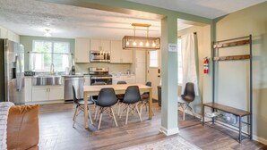 A modern kitchen with stainless steel appliances, a dining area with a wooden table and black chairs, and a metal rack on the wall. - Serene Roseland Retreat Near Wintergreen Resort! (Roseland)
