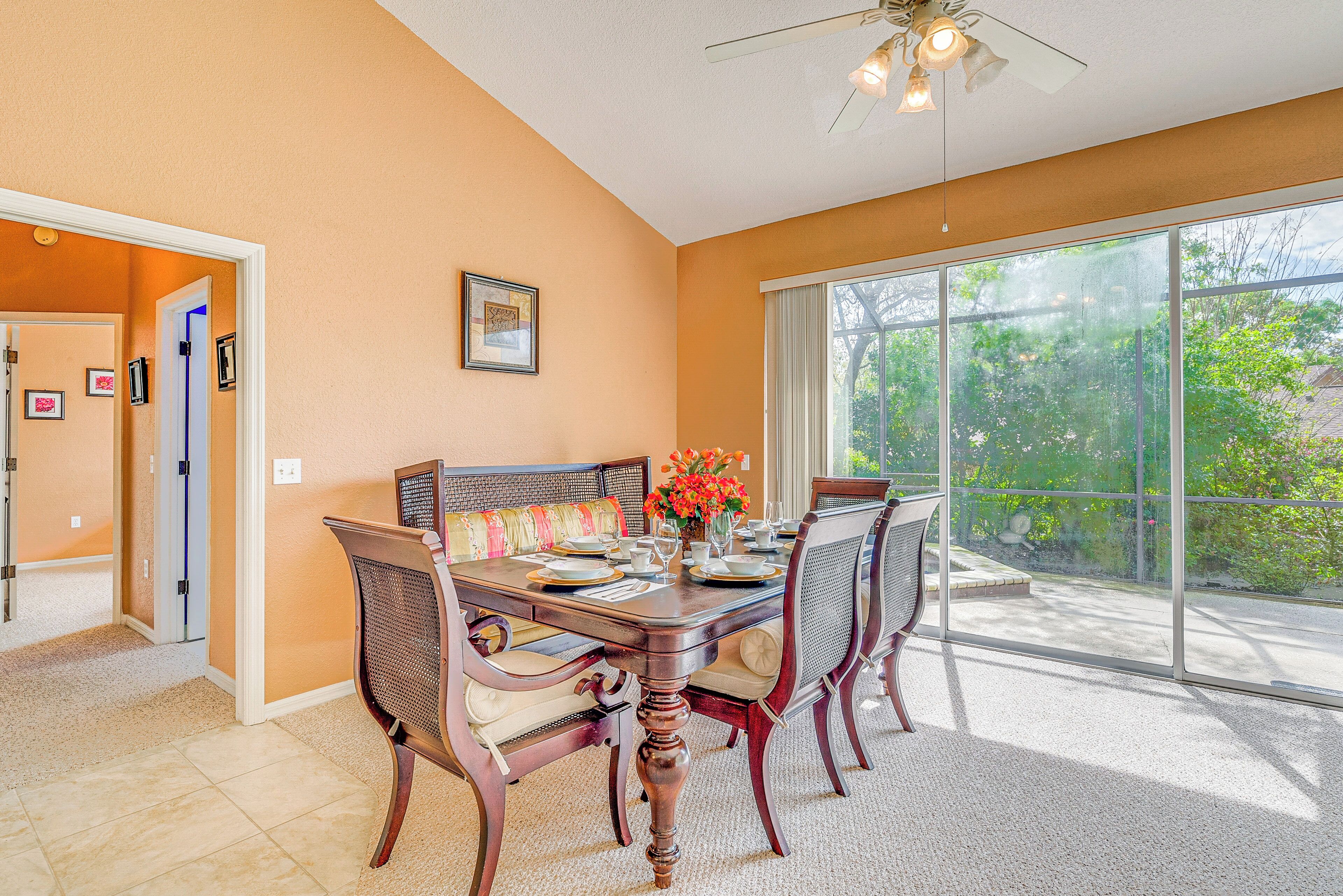 A dining area with a large window, a ceiling fan, and a dining table set for four.