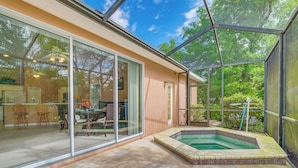A house with a glass-enclosed patio, a swimming pool, and a sliding glass door leading to a dining area.