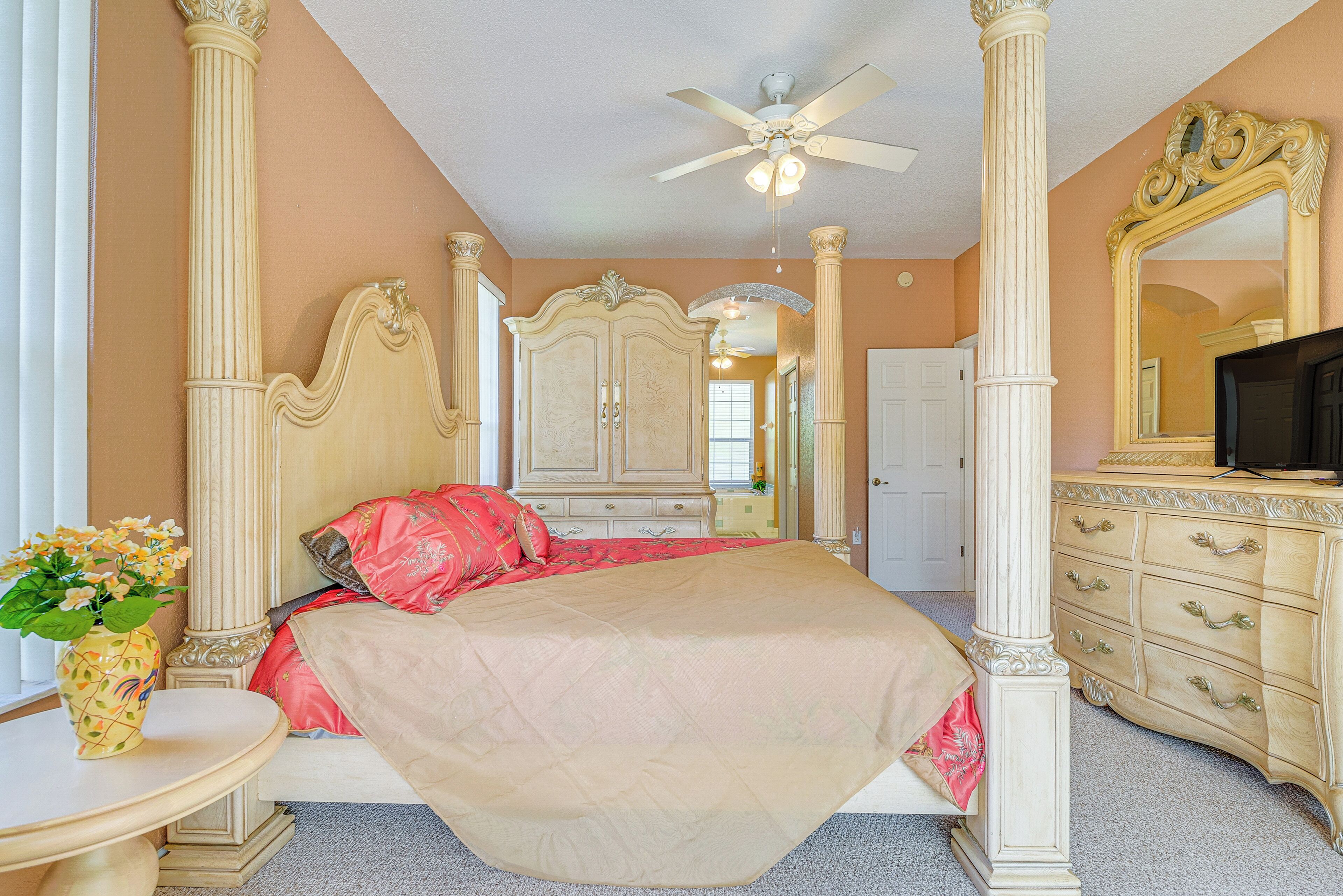 A bedroom with a bed, a dresser, a mirror, and a ceiling fan.
