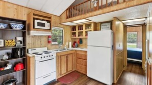 A compact kitchen with wooden cabinets, a stove, microwave, and refrigerator. - Cabin 9 ~ Toronto Lake: Fishing, Swimming & More! 1 Bedroom Cabin by RedAwning (Toronto)