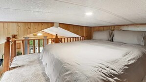 A bedroom with a large bed, wooden walls, a balcony with a railing, and a view of the outdoors. - Cabin 9 ~ Toronto Lake: Fishing, Swimming & More! 1 Bedroom Cabin by RedAwning (Toronto)