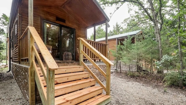 A wooden cabin with a porch and a staircase leading to a glass door entrance. - Cabin 9 ~ Toronto Lake: Fishing, Swimming & More! 1 Bedroom Cabin by RedAwning (Toronto)