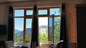A room with large windows, a desk, and a chair. - Hotel Leh Residency (Leh)