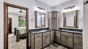Une salle de bain avec deux lavabos, des meubles en bois et un ventilateur de plafond.