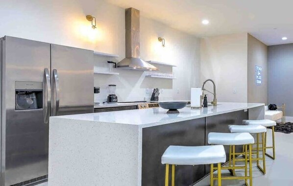 A modern kitchen with stainless steel appliances, a central island with stools, and a built-in oven.