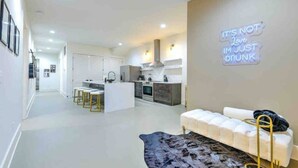 A modern kitchen with white cabinets, a central island, and a neon sign on the wall. - Walk 2 Broadway 15 beds! Private Hot Tub & Pool (Nashville)
