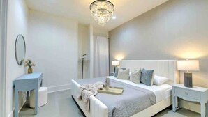 A modern bedroom with a large bed, bedside tables, a mirror, and a chandelier. - Walk 2 Broadway 15 beds! Private Hot Tub & Pool (Nashville)