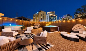 An outdoor lounge area with seating, a hot tub, and a view of the city skyline at night. - 14 Beds Walk 2 Broadway Hot Tub Pool Sauna Firepit (Nashville)