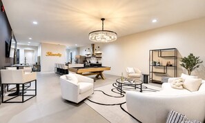 Una sala de estar moderna con mesa de billar, sofás y comedor.
