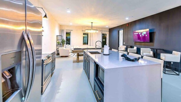 A modern kitchen with a central island, stainless steel appliances, and a flat-screen TV mounted on the wall. - New-14 Beds! Walk to broadway|Private Hot Tub/Pool (Nashville)