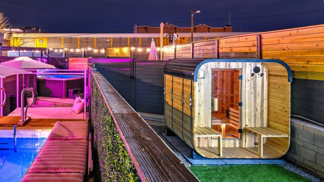 Une cabane en bois avec un banc à l’intérieur, une piscine et un espace abrité avec des sièges.