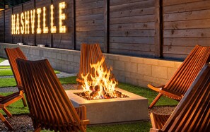 Un foyer avec des chaises disposées devant, un mur en bois orné de lettres lumineuses formant le mot « NASHVILLE », et une zone herbeuse.
