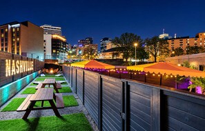 A rooftop patio with outdoor seating, a city skyline in the background, and a sign that reads 'NASHVILLE'. - 14 Beds Walk 2 Broadway Hot Tub Pool Sauna Firepit (Nashville)